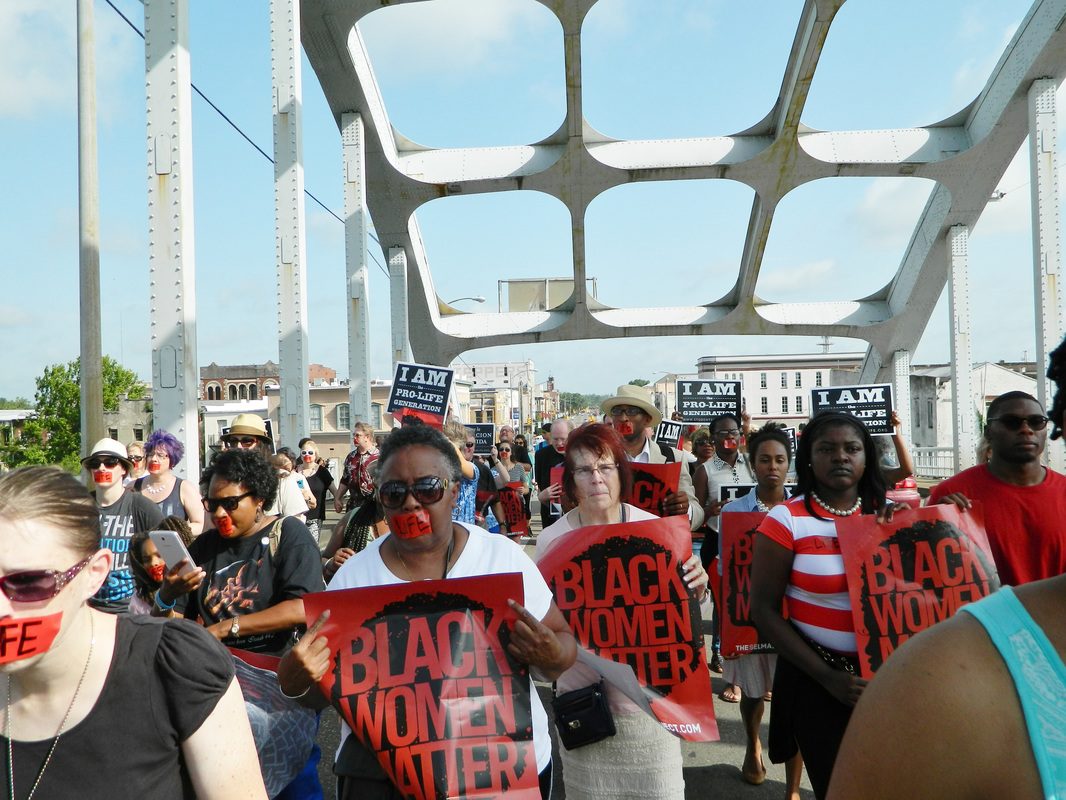 A group of people holding signs on top of a bridge.