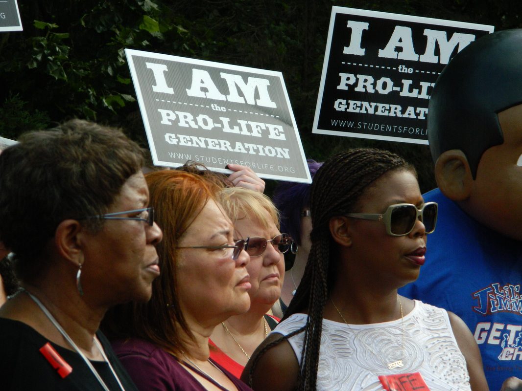 A group of people holding signs that say " i am the pro-life generation ".