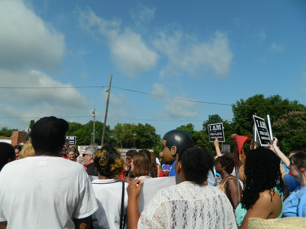 A crowd of people holding signs and standing in the street.