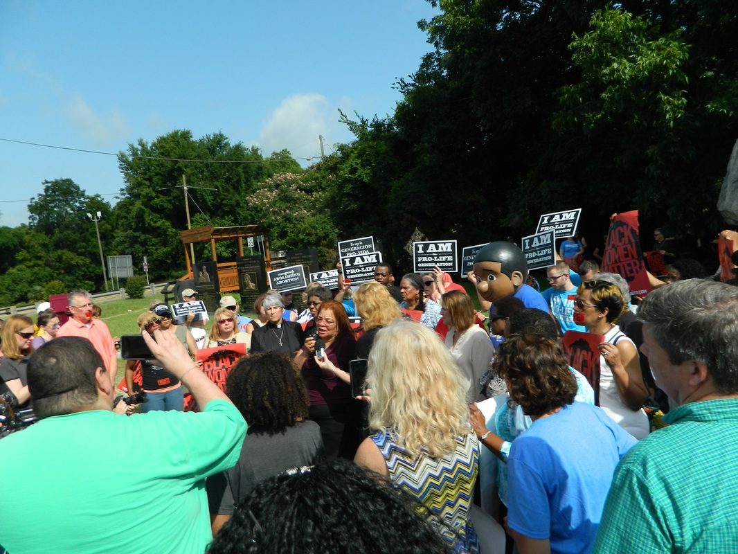 A crowd of people standing around holding signs.