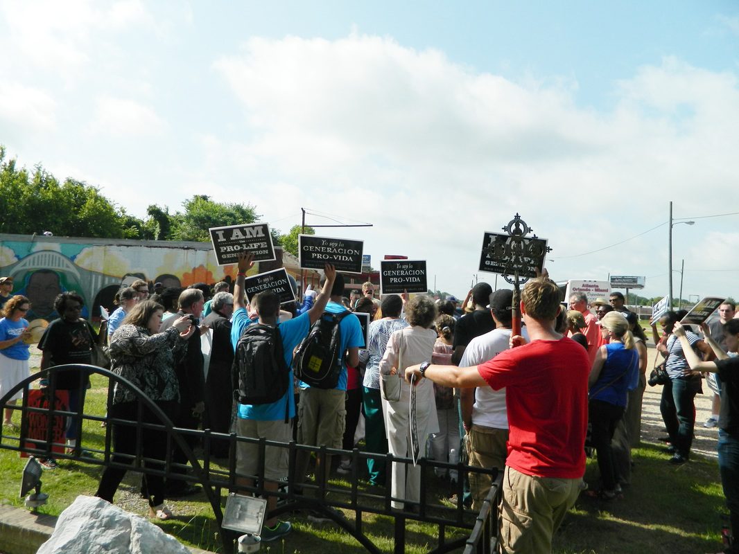 A group of people holding signs in front of a fence.